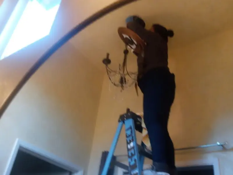 Electrician installing a chandelier in a Clifton residence